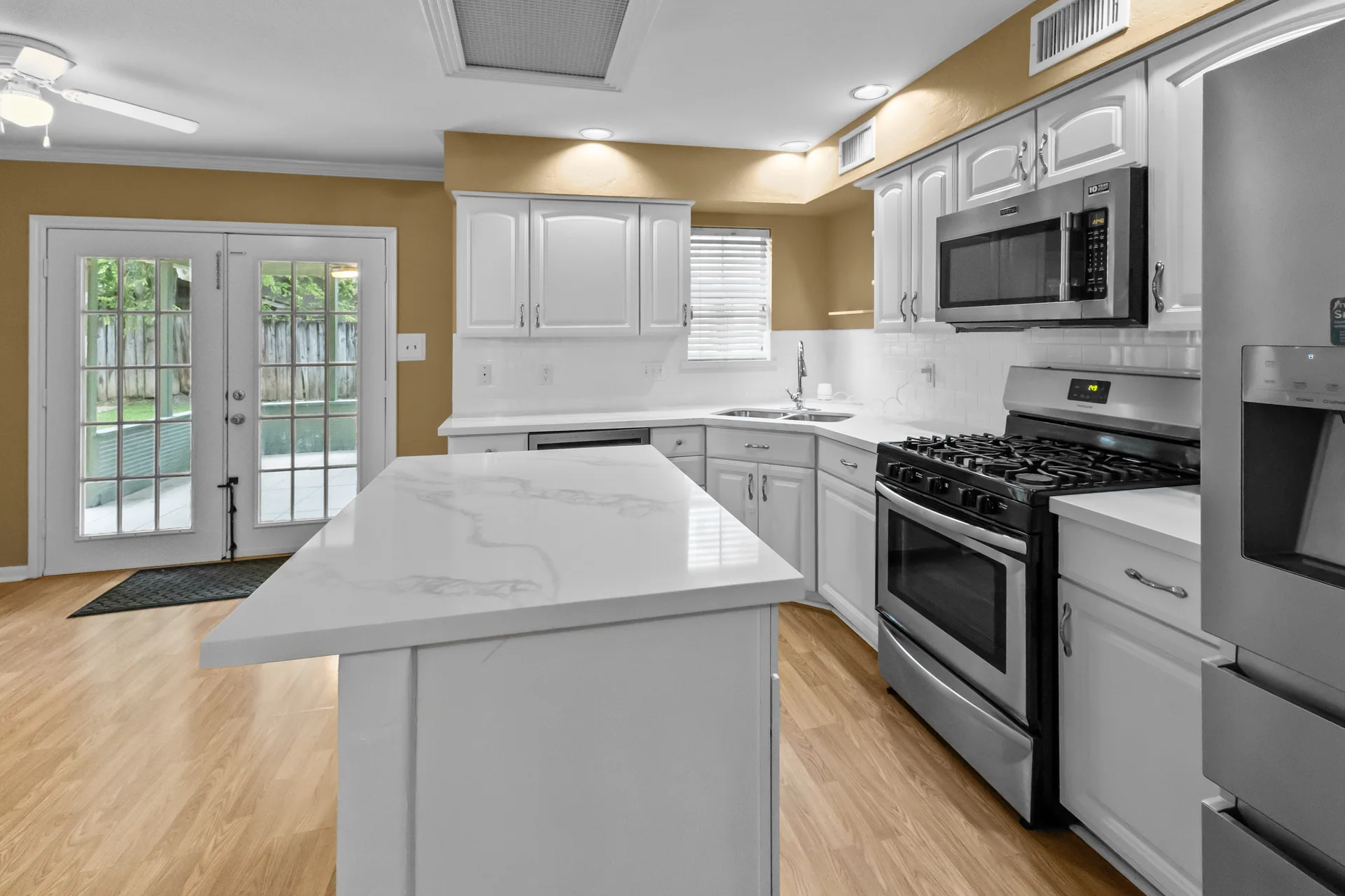 Updated kitchen with white cabinetry and stainless appliances