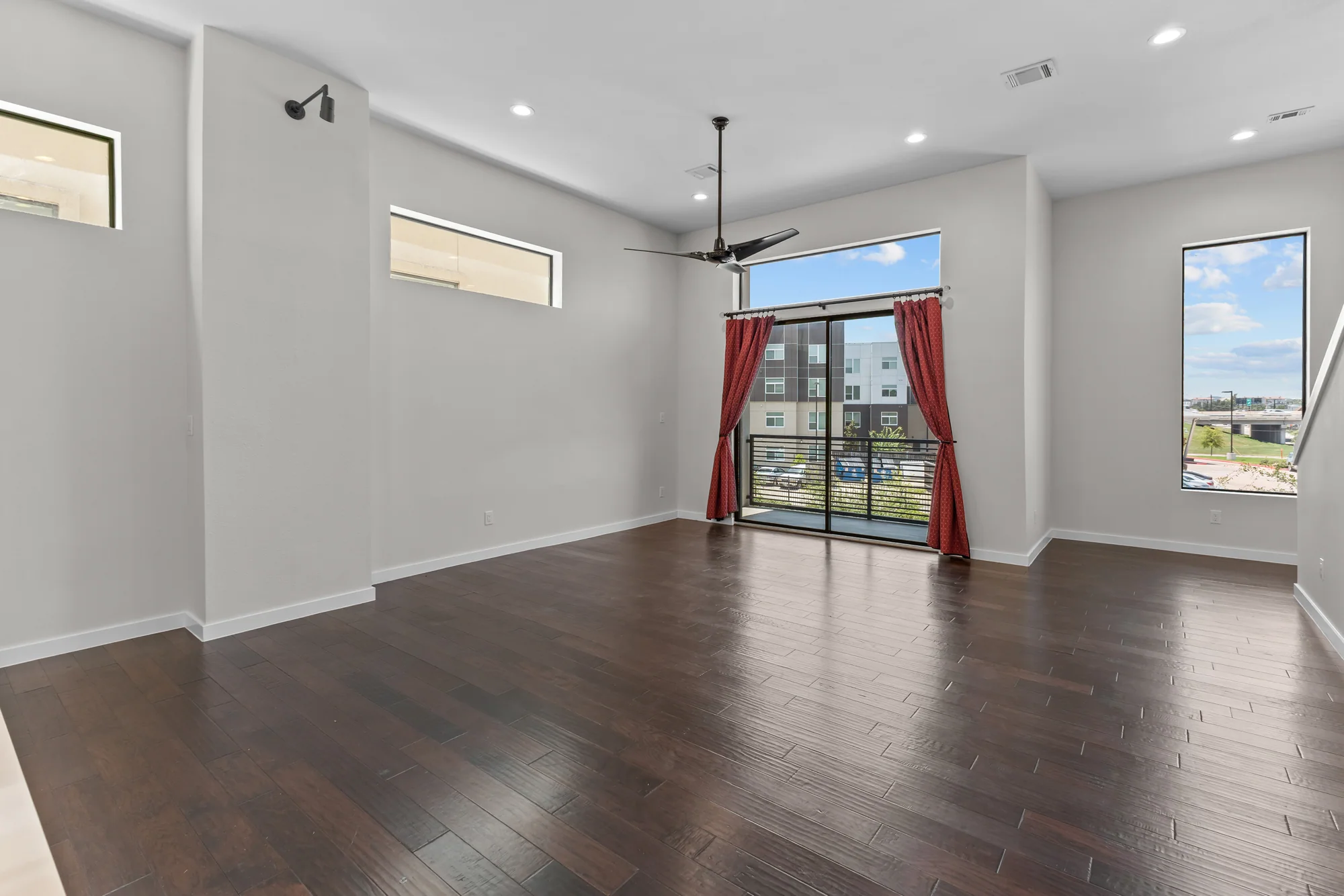 Open living room with balcony doors and dark wood floors