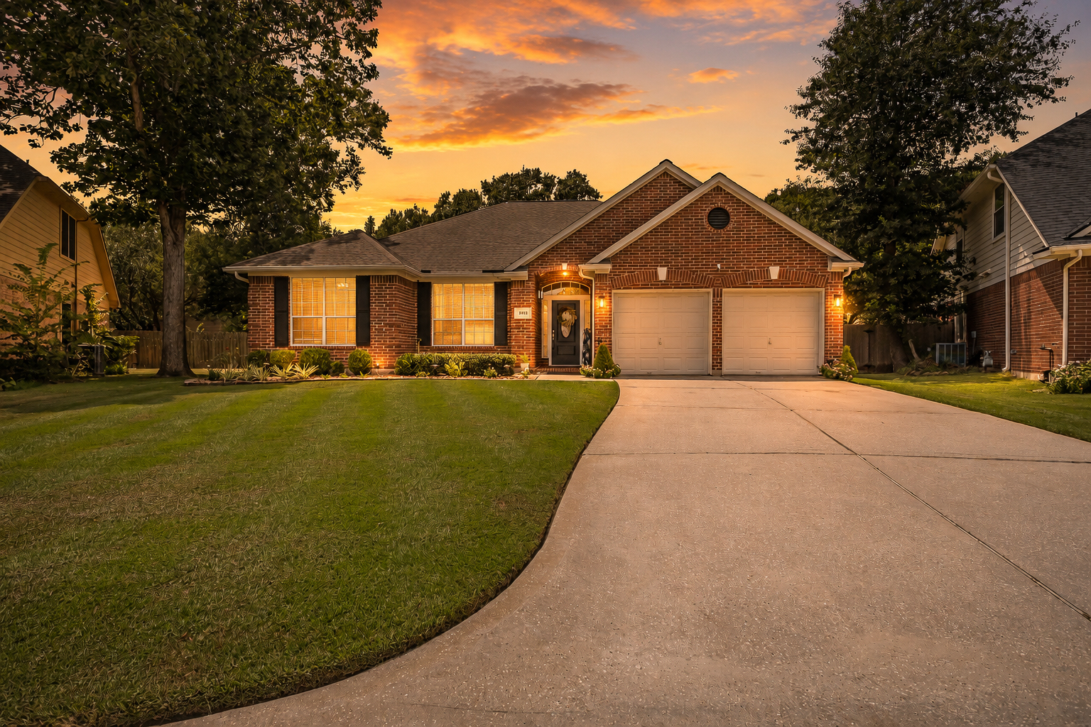 Brick suburban home glowing beneath a warm evening sky