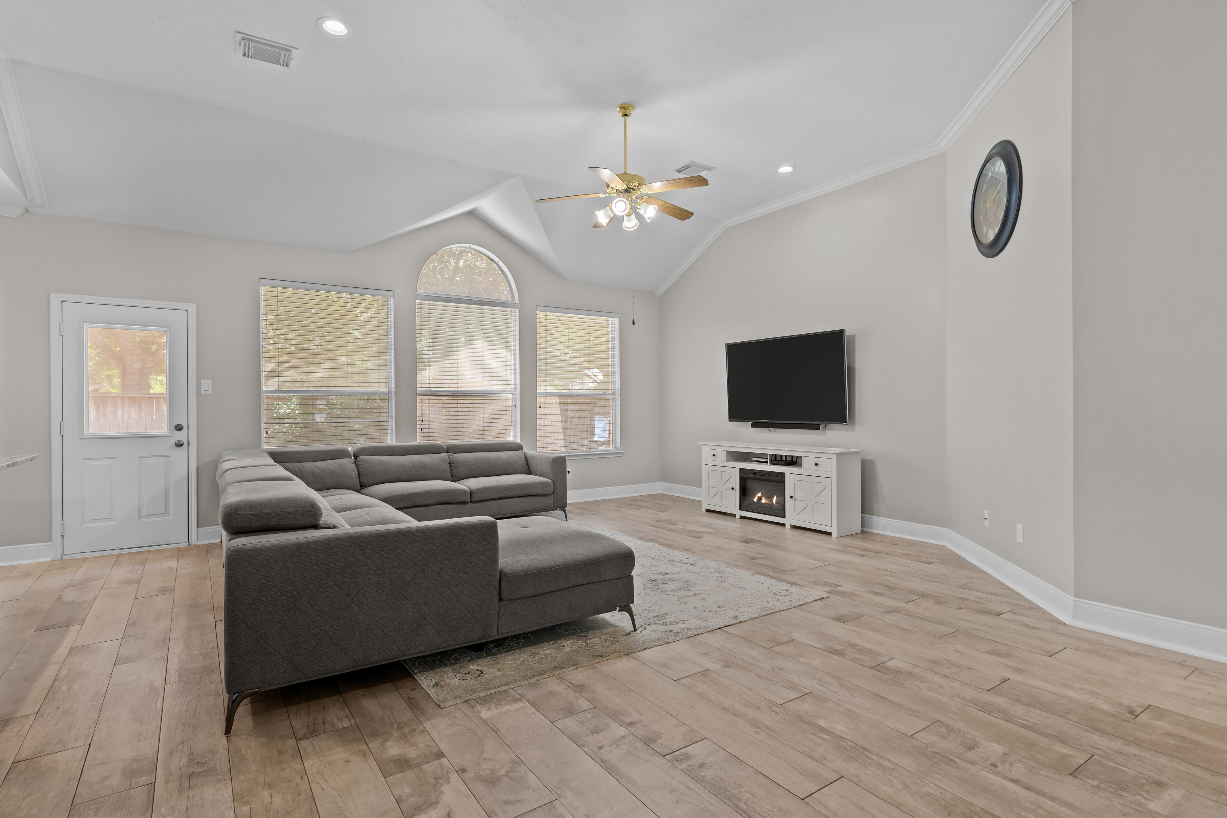 Spacious furnished living room with vaulted ceiling and large windows