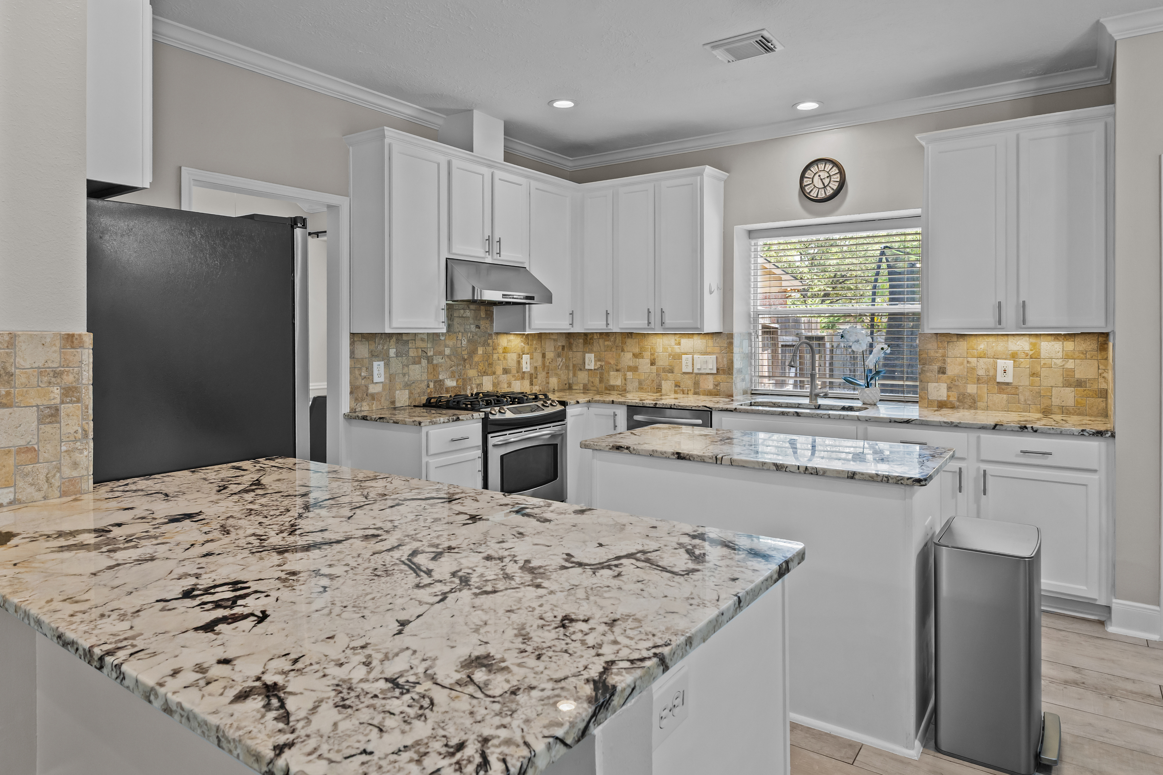 White kitchen cabinetry with stone counters and island