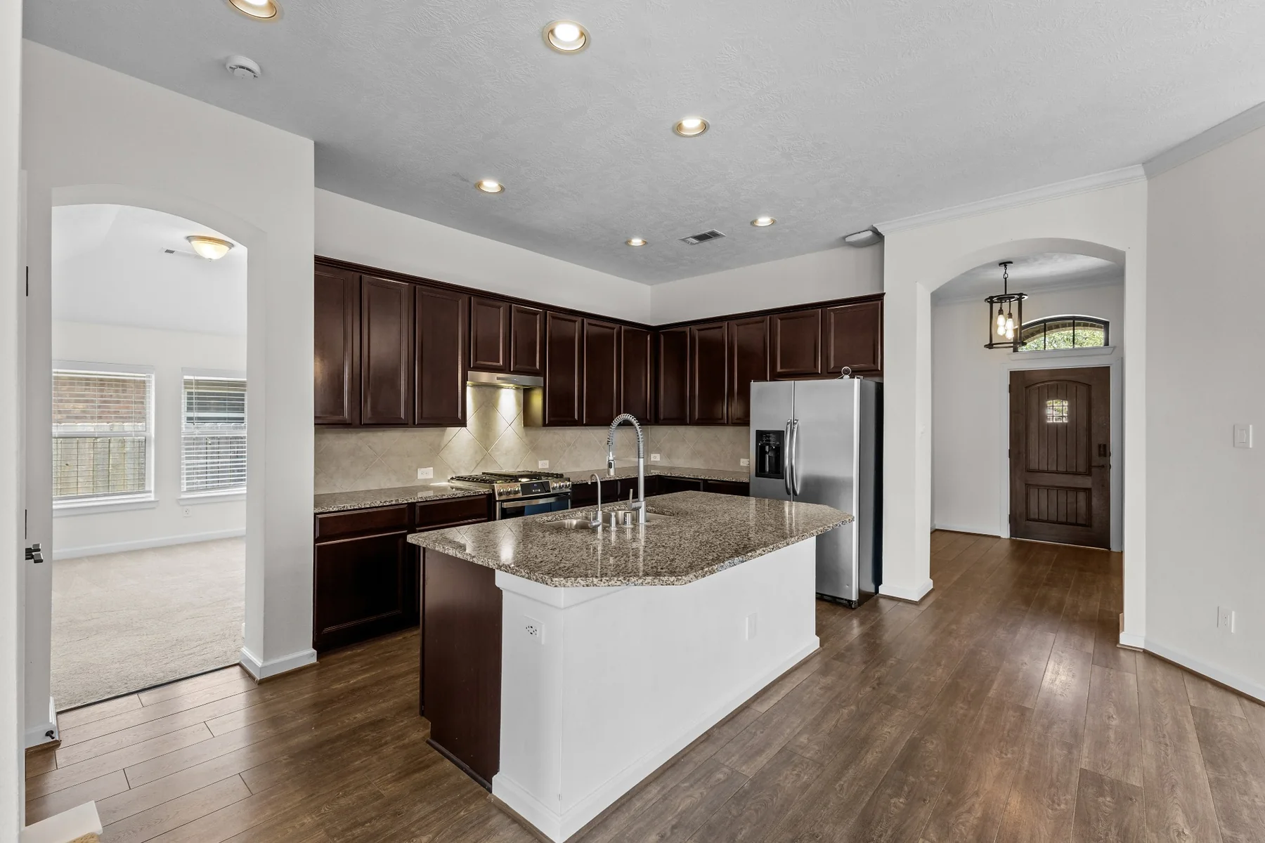 Angled view of kitchen with granite island and open floor plan
