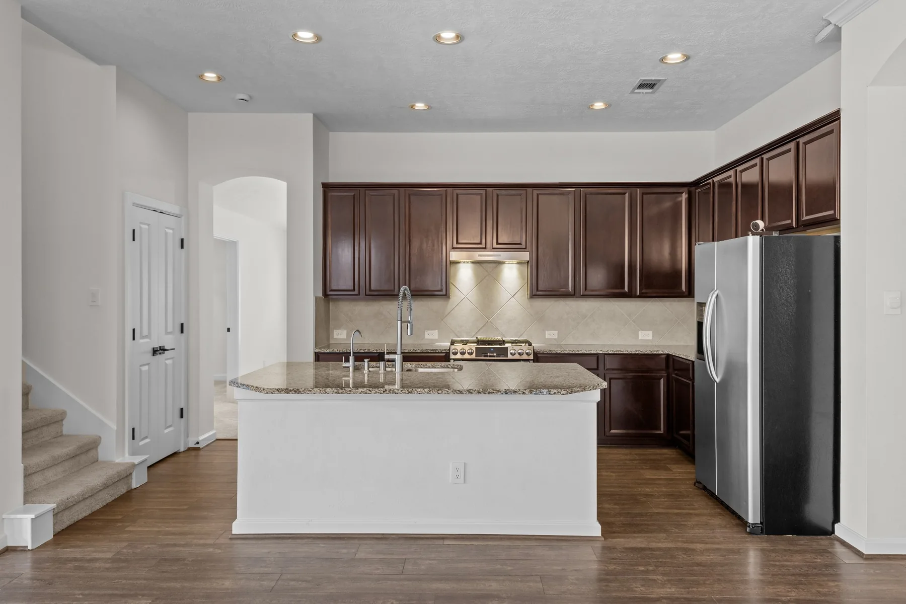 Kitchen with dark wood cabinetry, granite island, and stainless appliances