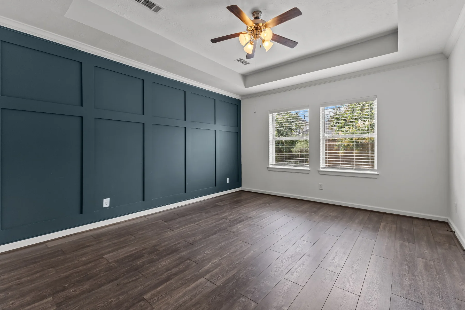 Primary bedroom with tray ceiling and dark accent wall