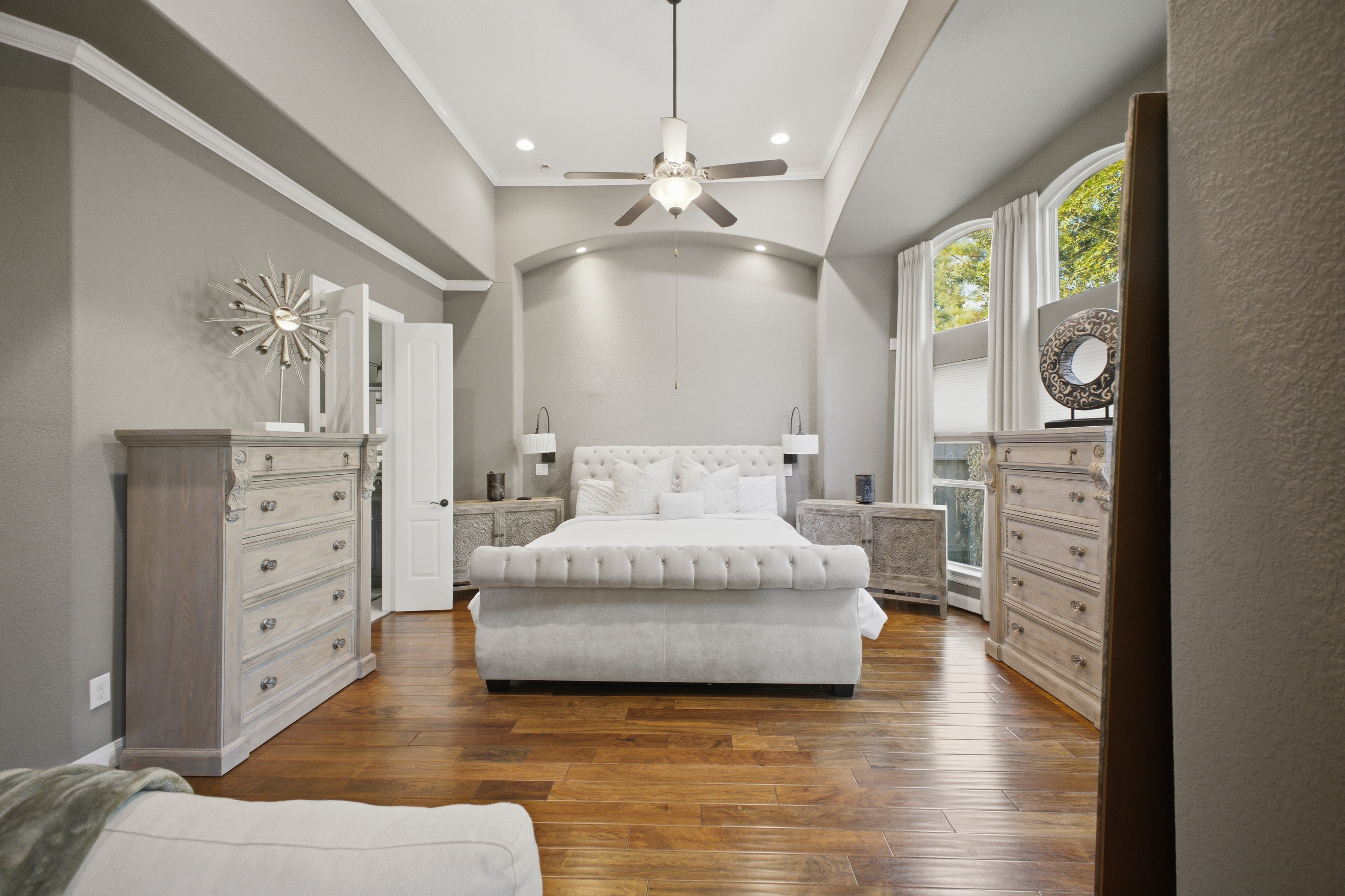Primary bedroom with hardwood floors and arched windows