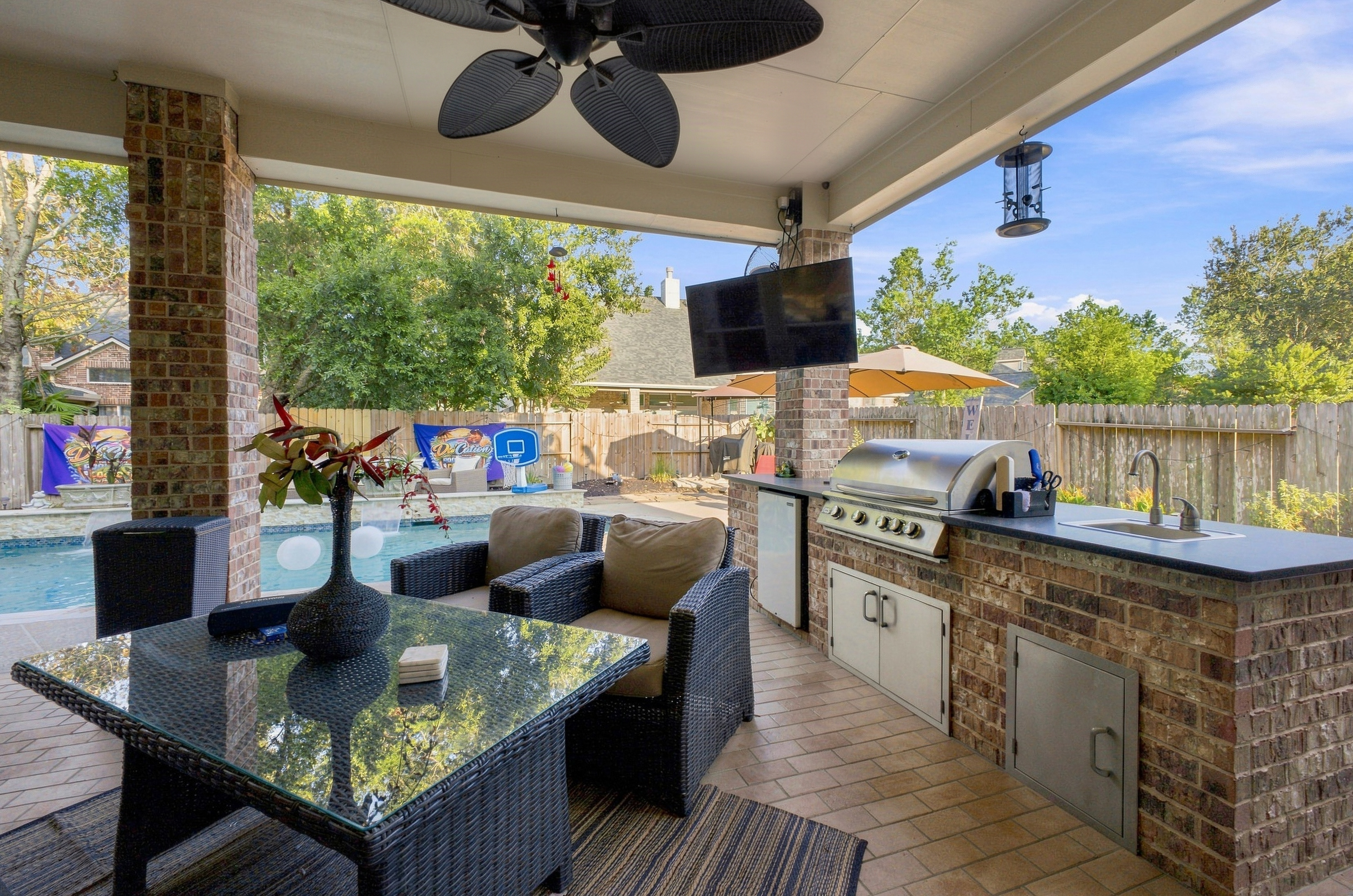 Covered outdoor kitchen and seating area beside the pool