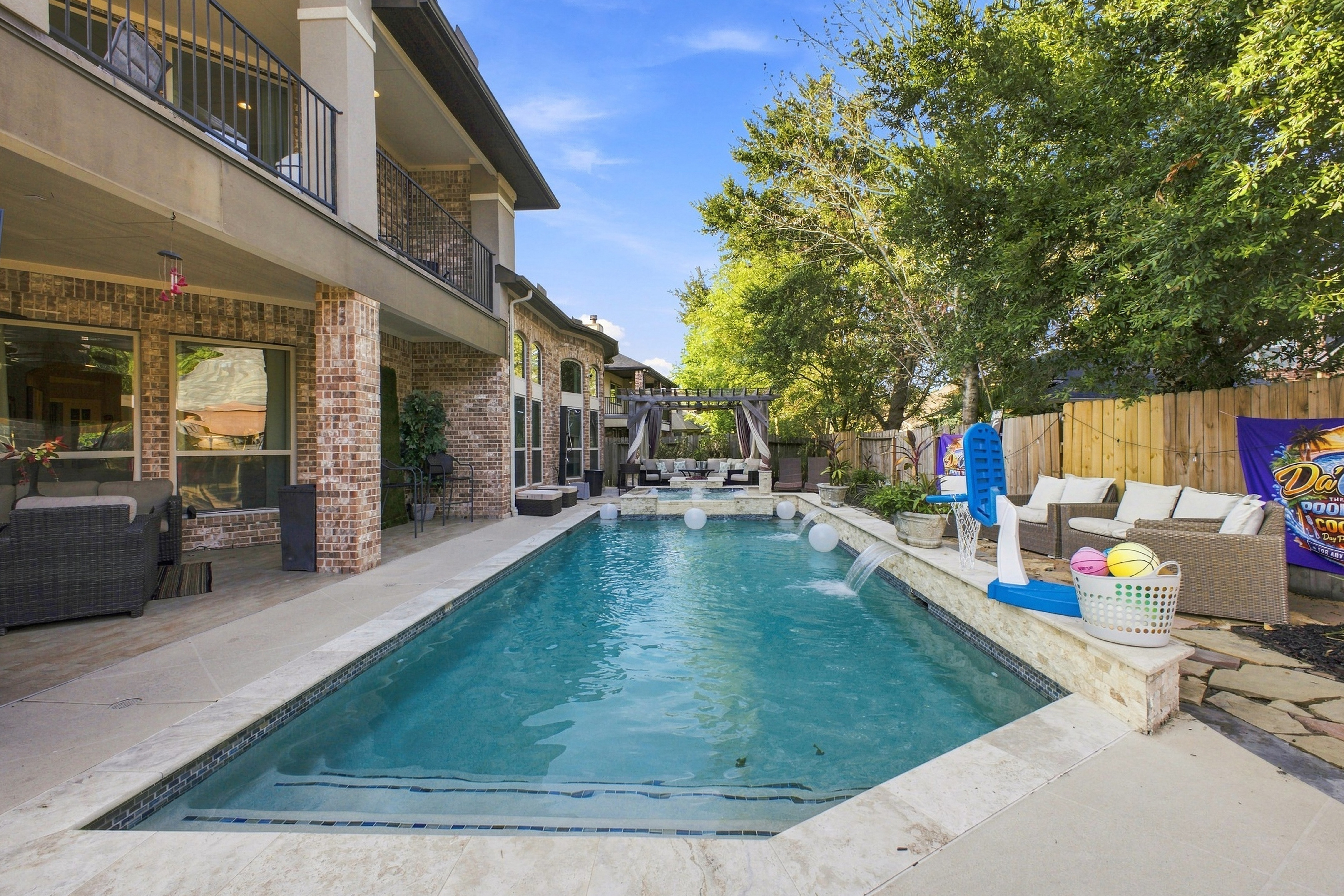 Wide backyard view featuring swimming pool and covered patios